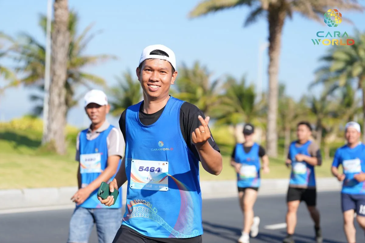 Vận động viên nam số 5464 mỉm cười giơ tay chào trên đại lộ cọ dừa CaraWorld Cara Run 2026 Vận động viên nam số 5464 mỉm cười giơ tay chào trên đại lộ cọ dừa CaraWorld Cara Run 2026