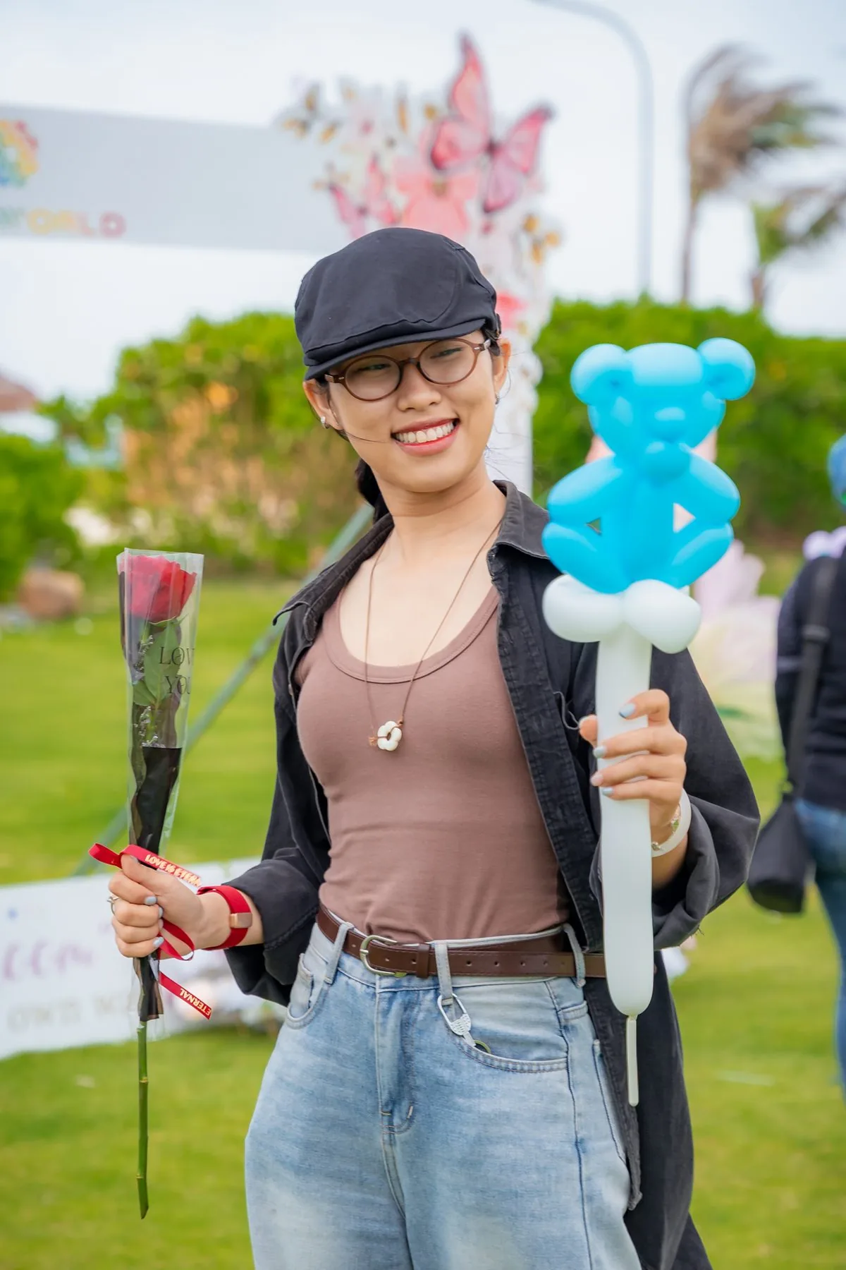 Cô gái trẻ cầm hoa hồng và bóng bay hình gấu tại sự kiện Bloom mừng 8 tháng 3 CaraWorld