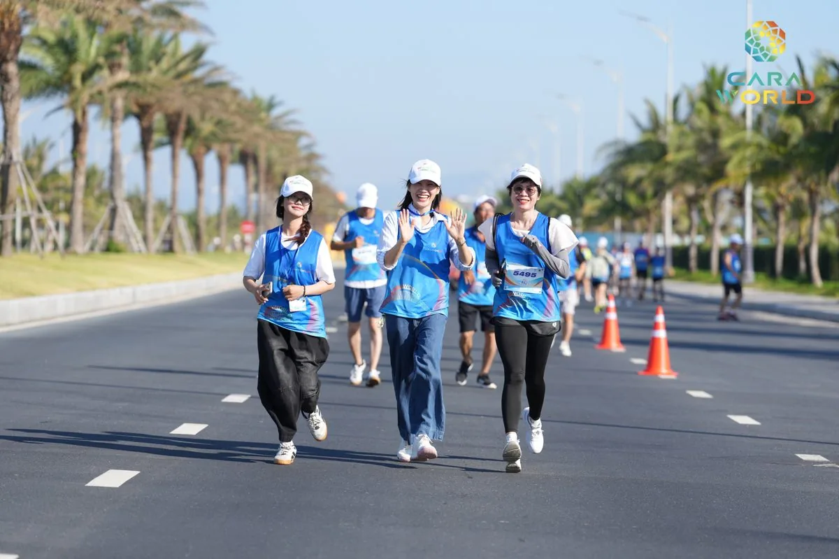 Ba nữ vận động viên vẫy tay chào đi bộ trên đại lộ ven biển CaraWorld giải Cara Run 2026