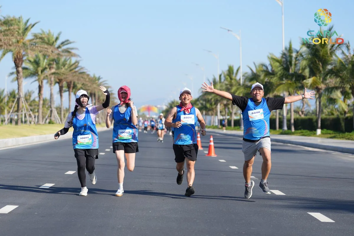Bốn vận động viên vui vẻ nắm tay chạy trên đại lộ ven biển CaraWorld giải Cara Run 2026